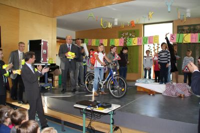 ADAC-Vorstandsmitglied Josef Kaspar �berbrachte am Ende eines Verkehrstheaterst�ckes der Kombiklasse 3c/4c reflektierende Sicherheitswesten f�r die Erstkl�ssler. Staatssekret�r Bernd Sibler (links) vom Bayerischen Staatsministerium f�r Unterricht und Kultus w�rdigte die Initiative und half zusammen mit den Vertretern der Partner der Gemeinschaftsaktion bei der Verteilung der Warnwesten